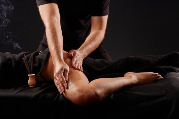 handsome-male-masseur-doing-massage-girl-s-leg-black-background-concept-therapeutic-relaxing-massage_627378-7796