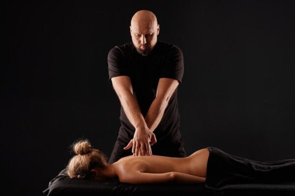 handsome-male-masseur-giving-massage-girl-black-background-concept-therapeutic-relaxing-massage_627378-7774
